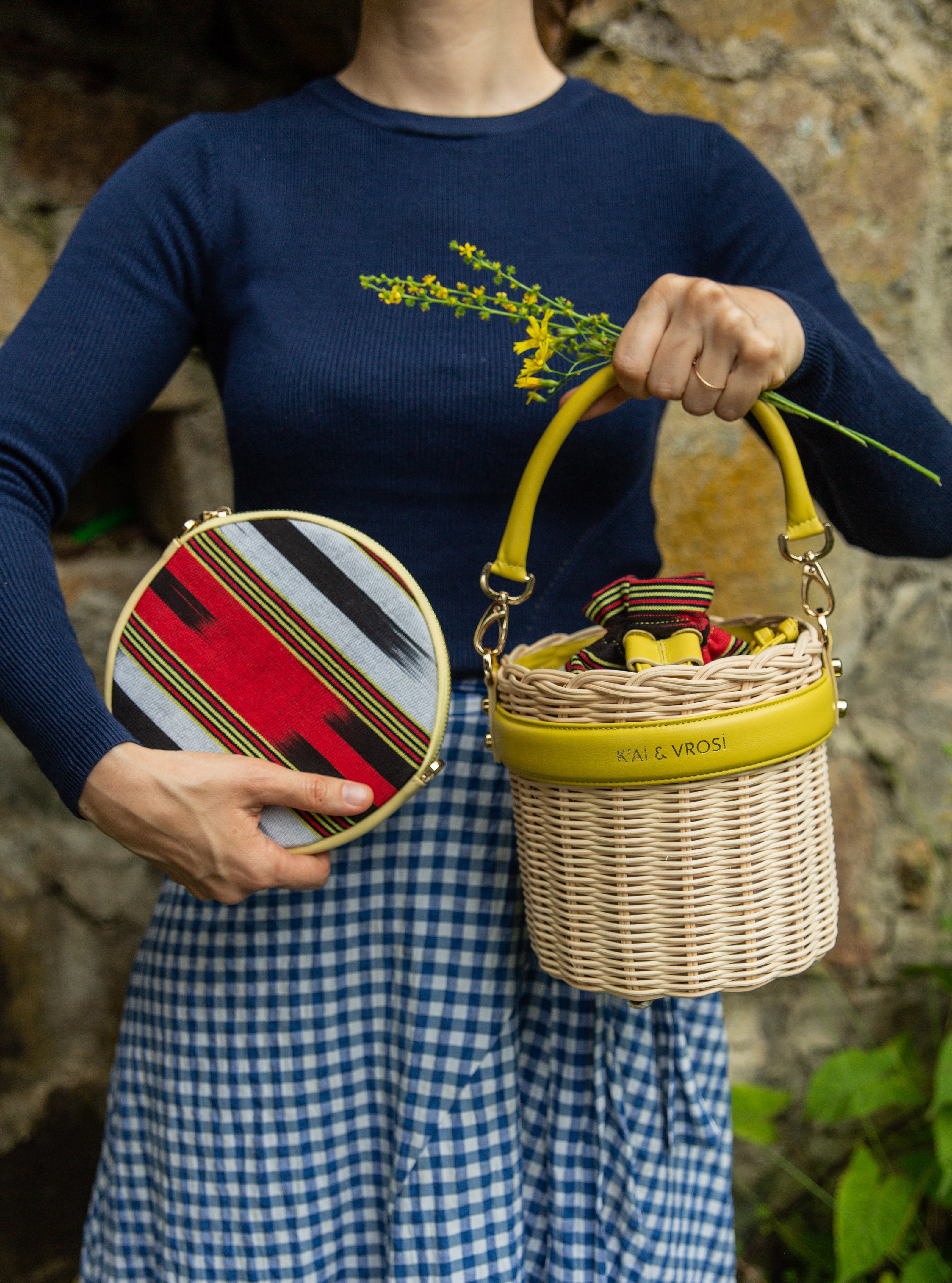 A woman holding our leather crossbody bag Cona Maxi and round shaped yellow leather rattan handbag Okordule